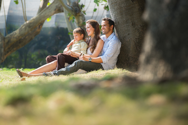 Happy family with man woman and child leaning on tree in city park copy space sbi 310156660